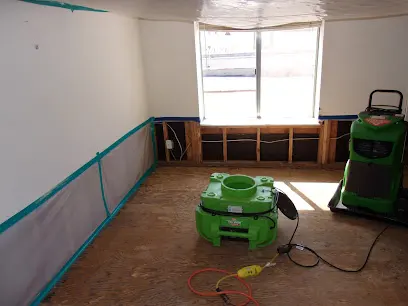 Room with the lower drywall cut out and drying equipment running on the bare subfloor
