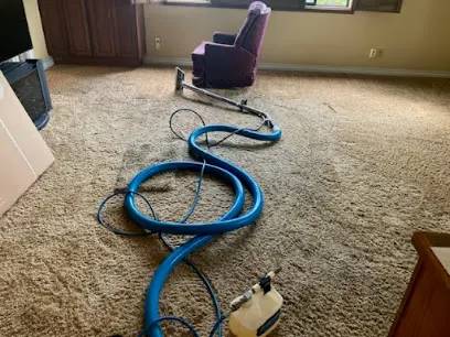 An extraction hose and wand pulling water out of wet carpet