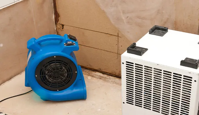 Air mover on the floor drying a San Dimas room with the lower part of the wall cut open