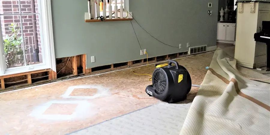 An air mover drying a Covina room with the lower wall opened so wet drywall and framing can dry out.