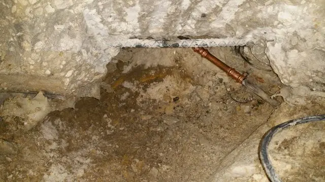 Copper water pipe exposed in a broken-out section of a concrete slab floor