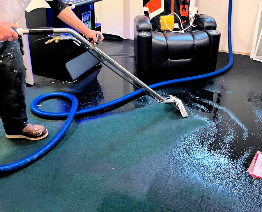 Extraction wand pulling water out of soaked carpet in a home theater room